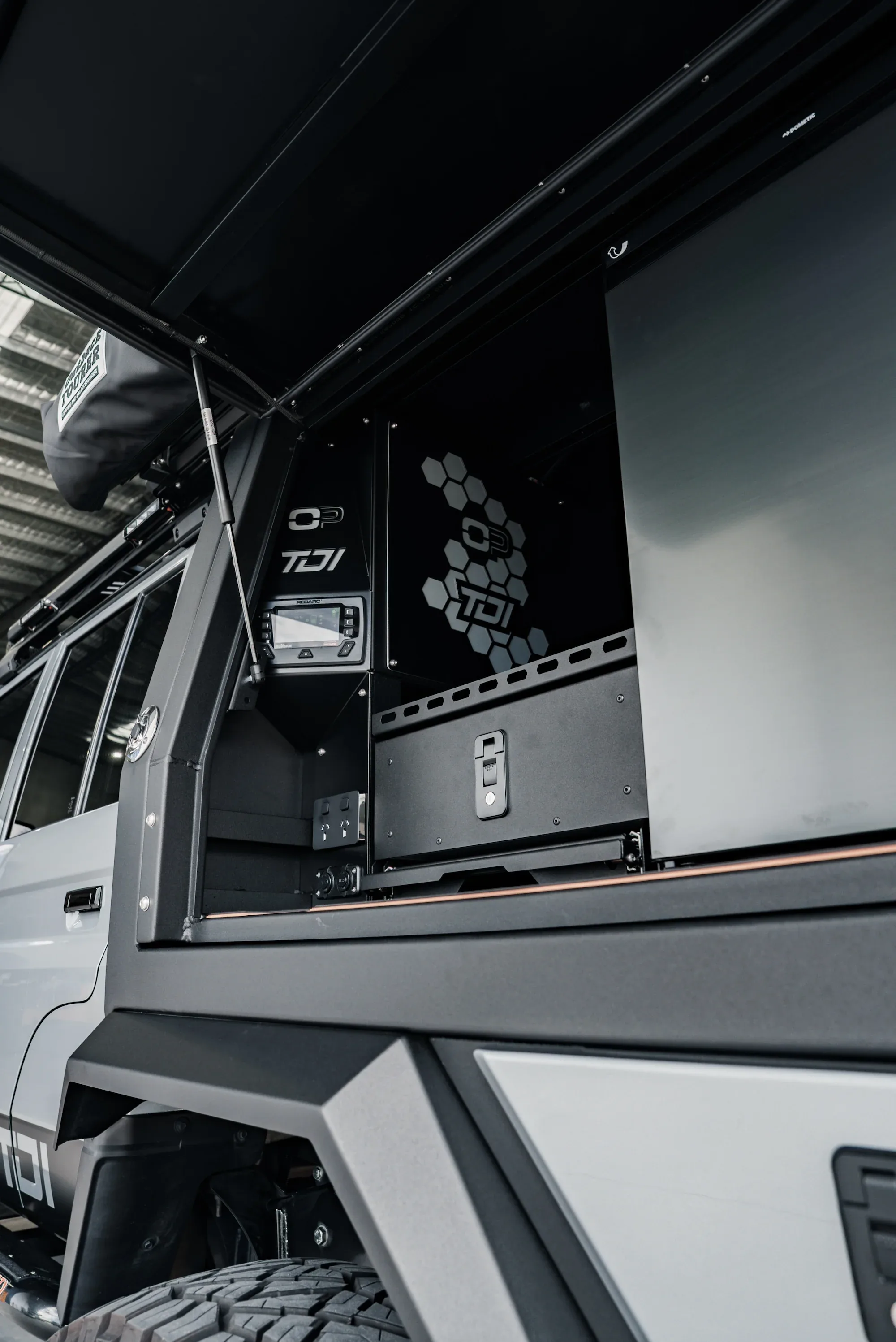 A 79 Series TDI canopy open, a REDARC battery management display and power outlets beside the drawer.