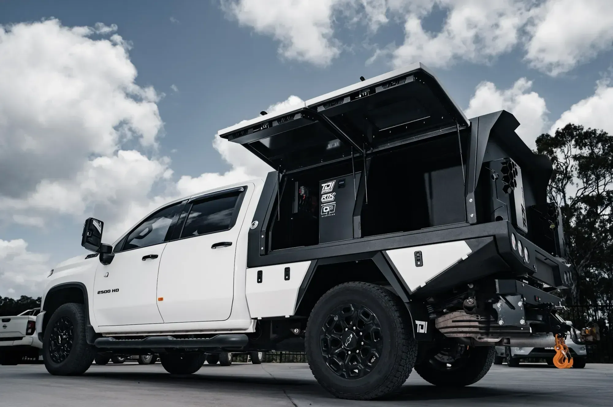A white 2500HD dual cab with a black TDI tray and canopy, both canopy doors up, tow hitch at the rear.