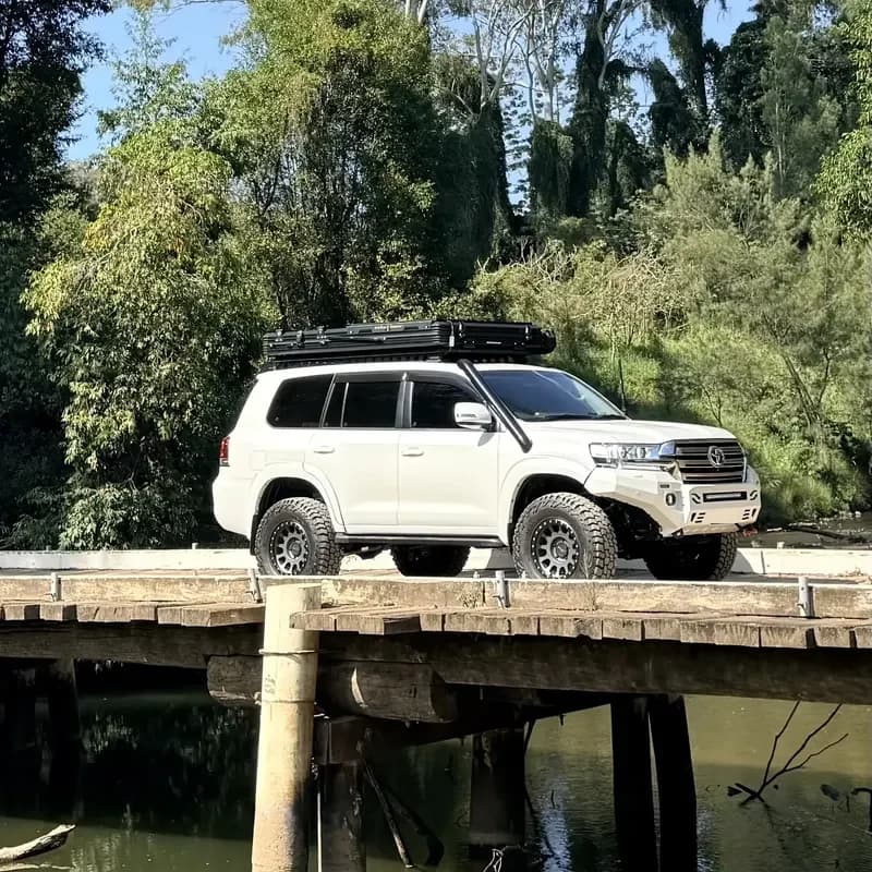 A 200 Series crossing a timber bridge over a creek.